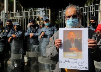 An anti-government activist holds a picture of assassinated Lebanese prominent Shiite Muslim intellectual and Lukman Sleim on Thursday. The 58-year-old was shot four times in the head near the village of Addousiyeh in southern Lebanon, which is mainly controlled by Hezbollah. Photo: Marwan Naamani/dpa