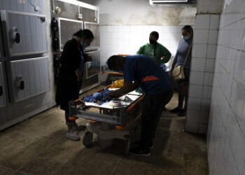 Wendy Dulcey (L) and her husband prepare the body of their one-month-old son who died in the intensive care room of the University Hospital in Caracas on January 10, 2021. - Infant mortality in Venezuela increased 30.12% in 2016, with 11,466 deaths of children aged 0 to 1 year, and maternal mortality soared 65%, according to the latest figures published by the Ministry of Health. (Photo by Yadira PEREZ / AFP)