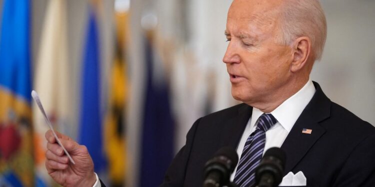 US President Joe Biden looks at a card he pulled from his pocket to read the number of Americans who have died of Covid-19 to date, as he speaks on the anniversary of the start of the Covid-19 pandemic, in the East Room of the White House in Washington, DC on March 11, 2021. (Photo by MANDEL NGAN / AFP)