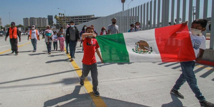 Familias de migrantes marchan hoy en las inmediaciones del cruce fronterizo de El Chaparral, en Tijuana (México). Con una sesión de oración, de la religión católica, un centenar de migrantes centroamericanos pidieron este miércoles en la ciudad de Tijuana la intercesión de Dios para que los "ayude" con la apertura de la frontera de Estados Unidos. Las plegarias de los migrantes se extendieron por poco más de una hora, tiempo en el que elevaron su voz y recordaron que su compañero en su travesía ha sido Dios, en quien expresaron su confianza para que el presidente Joe Biden cumpla la promesa de abrir las fronteras. EFE/Joebeth Terríquez