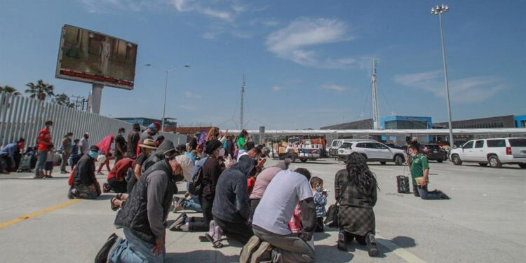 Migrantes rezan hoy en las inmediaciones del cruce fronterizo de El Chaparral, en Tijuana (México). Con una sesión de oración, de la religión católica, un centenar de migrantes centroamericanos pidieron este miércoles en la ciudad de Tijuana la intercesión de Dios para que los "ayude" con la apertura de la frontera de Estados Unidos. Las plegarias de los migrantes se extendieron por poco más de una hora, tiempo en el que elevaron su voz y recordaron que su compañero en su travesía ha sido Dios, en quien expresaron su confianza para que el presidente de Joe Biden cumpla la promesa de abrir las fronteras. EFE/Joebeth Terríquez