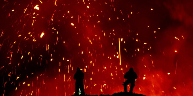 A picture taken on March 16, 2021 shows people watching Klyuchevskoy volcano eruption on Russia's far eastern Kamchatka peninsula. - The eruption of a volcano on a Russian peninsula has attracted thrill-seeking tourists risking their lives for picturesque photos, prompting concerns in recent days from local emergency responders. (Photo by MAXIM FESYUNOV / AFP)