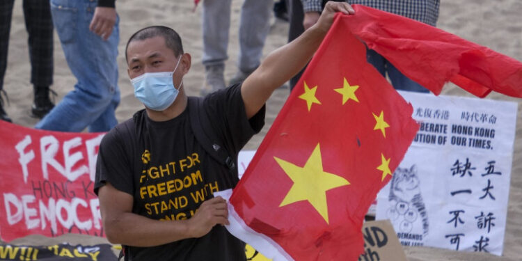 (FILES) In this file photo a member of local natives of Hong Kong shows a broken Chinese flag during a flash mob march to show solidarity with the 47 pro-democracy activists in Hong Kong who were charged for state subversion due to them organizing and taking part in a primary election, in Santa Monica, California on March 7, 2021. - The United States reaffirmed on March 31, 2021 that Hong Kong has lost its autonomy from China as it vowed to pressure Beijing for dismantling the city's special status.A day after China approved a radical overhaul of Hong Kong's political system, Secretary of State Antony Blinken in a required report to Congress found that the financial hub "does not warrant different treatment under US law" from the mainland. (Photo by RINGO CHIU / AFP)