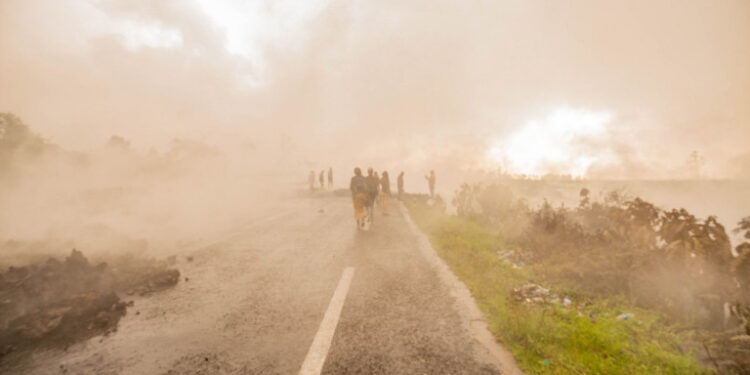 Residents walk through the smoke from smouldering lava flewing from Mount Nyiragongo in Goma on May 23, 2021. - A river of boiling lava came to a halt on the outskirts of Goma Sunday, sparing the city in eastern DR Congo from disaster after the nighttime eruption of Mount Nyiragongo sent thousands of terrified residents fleeing in panic.
Fire and strong fumes emanated from the blackish molten rock as it swallowed up houses, heading towards Goma airport on the shores of Lake Kivu. (Photo by Moses Sawasawa / AFP)