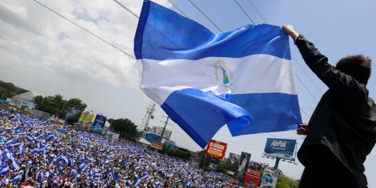 A man waves a Nicaraguan flag as people participate in a demonstration called the "March of the Flowers" remembering the children killed during the last two-months violence, in Managua, Nicaragua, Saturday, June 30, 2018. The Central American nation has been rocked since April 19 by daily chaos as protesters maintaining roadblocks and demanding Ortega's ouster are met by a heavy-handed crackdown by security forces and allied civilian groups. (AP Photo/Alfredo Zuniga)