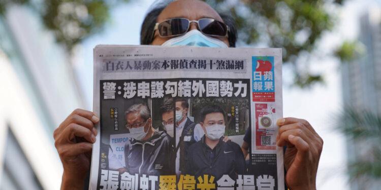 A supporter holds a copy of Apple Daily newspaper during a court hearing outside West Magistrates’ Courts, after police charge two executives of the pro-democracy Apple Daily newspaper over the national security law, in Hong Kong, China, June 19, 2021. REUTERS/Lam Yik