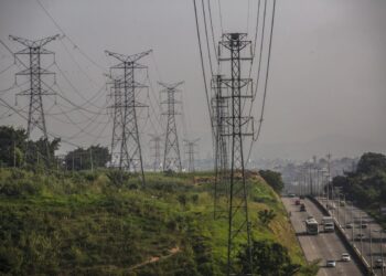 Vehicles travel along a road next to Centrais Eletricas Brasileiras SA (Eletrobras) transmission towers in Rio de Janeiro, Brazil, on Friday, May 21, 2021.  Brazil’s lower house approved the main text of a bill that paves the way for the privatization of state utility Eletrobras. Photographer: Dado Galdieri/Bloomberg