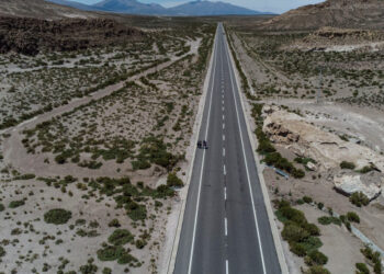 Aerial view of Venezuelan migrants Reinaldo, 26, Anyier, 40, and her daughter Danyierly, 14, walking along the highway on their way to Iquique, after crossing from Bolivia, in Colchane, Chile, on February 18, 2021. - Crossing the highlands of the border between Bolivia and Chile on foot is the hardest part of the journey Venezuelan migrants go through on their way to Iquique or Santiago. (Photo by MARTIN BERNETTI / AFP)