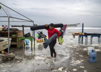 A woman removes umbrellas from the beach as strong waves reach the coast due to Hurricane Grace, which has reached category 2, in Boca del Rio, Veracruz, Mexico, on August 20, 2021. - Grace regained hurricane strength Friday as it barreled towards Mexico for a second time, triggering warnings of flooding and mudslides in mountains on the eastern mainland. (Photo by VICTORIA RAZO / AFP)