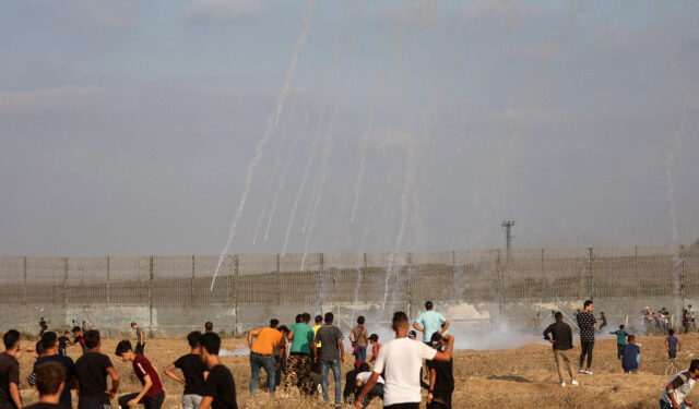 Palestinian protesters watch incoming tear gas canisters shot by Israeli security forces amid clashes following a demonstration near the border fence with Israel, east of Gaza City, to denounce the Israeli siege of the Palestinian strip and express support for Jerusalem's Al-Aqsa mosque, on August 21, 2021. - Israeli troops fired live rounds at Palestinian protesters who hurled firebombs and burned tyres from behind the Gaza Strip's border fence, with medics reporting 23 Palestinians injured. The protest called for by the Palestinian Hamas movement that rules Gaza marks the burning 52 years ago of Jerusalem's Al-Aqsa Mosque, the third-holiest site in Islam. (Photo by SAID KHATIB / AFP)