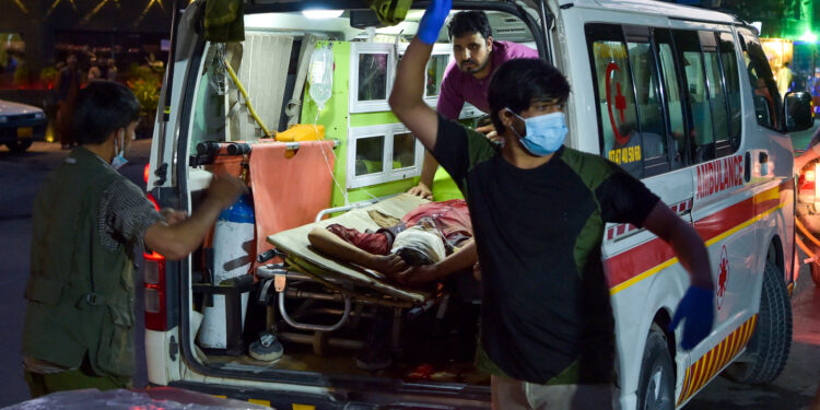 EDITORS NOTE: Graphic content / Medical staff bring an injured man to a hospital in an ambulance after two powerful explosions, which killed at least six people, outside the airport in Kabul on August 26, 2021. (Photo by Wakil KOHSAR / AFP)