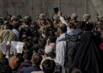 Un hombre sujeta su pasaporte delante de los militares que guardan el aertopuerto de Kabul. JUAN CARLOS