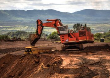 An excavator moves earth to a dump truck on the open mining site of Venezuelan iron ore producer, CVG Ferrominera Orinoco, on Bolivar Hill outside of Ciudad Piar, Venezuela, on Thursday, July 9, 2015. Photographer: Meridith Kohut/Bloomberg