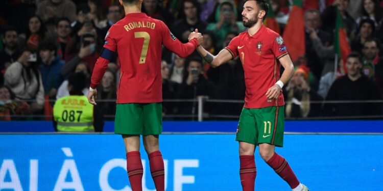 Portugal's midfielder Bruno Fernandes (R) celebrates with Portugal's forward Cristiano Ronaldo after scoring his team's second goal during the World Cup 2022 qualifying final first leg football match between Portugal and North Macedonia at the Dragao stadium in Porto on March 29, 2022. (Photo by MIGUEL RIOPA / AFP)