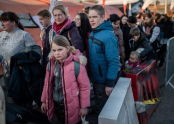 Refugiados procedentes de Ucrania hacen cola mientras esperan un nuevo transporte en el paso fronterizo de Medyka, en el sureste de Polonia, el 23 de marzo. (Foto de ANGELOS TZORTZINIS/AFP vía Getty Images).