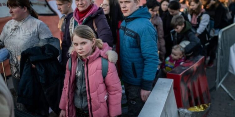 Refugiados procedentes de Ucrania hacen cola mientras esperan un nuevo transporte en el paso fronterizo de Medyka, en el sureste de Polonia, el 23 de marzo. (Foto de ANGELOS TZORTZINIS/AFP vía Getty Images).