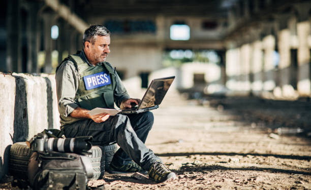 One man, war journalist with using laptop at the place of action, in war zone.