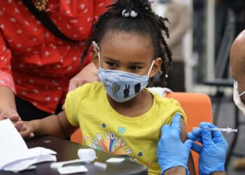 CHICAGO, ILLINOIS - NOVEMBER 12: A kindergarten student receives a COVID-19 vaccine at Michele Clark High School on November 12, 2021 in Chicago, Illinois. The city of Chicago closed all public schools today, declaring the day Vaccination Awareness Day, with the hope of getting as many students as possible vaccinated against COVID-19.  (Photo by Scott Olson/Getty Images)