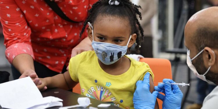 CHICAGO, ILLINOIS - NOVEMBER 12: A kindergarten student receives a COVID-19 vaccine at Michele Clark High School on November 12, 2021 in Chicago, Illinois. The city of Chicago closed all public schools today, declaring the day Vaccination Awareness Day, with the hope of getting as many students as possible vaccinated against COVID-19.  (Photo by Scott Olson/Getty Images)