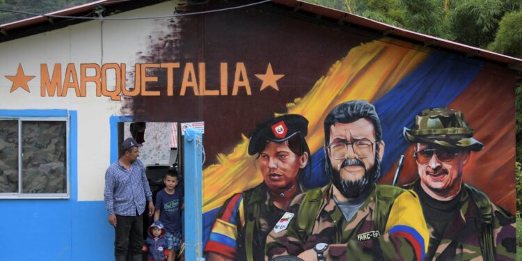 (FILES) In this file photo taken on October 27, 2021, a man and children stand next to a graffitis of late FARC commander Alfonso Cano (C) at El Oso Territorial Training and Reincorporation Area (ETCR), in Gaitania, Tolima Department, Colombia. - The US government has notified Congress that it will remove the official terror group designation from former rebels of the Revolutionary Armed Forces of Colombia (FARC), a congressional source told AFP on November 23, 2021. (Photo by Raul ARBOLEDA / AFP)