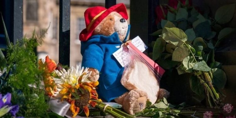 Los jardineros de la realeza fueron retirando de a poco el envoltorio de plástico de las flores colocadas, mientras que el público también han colaborado (Jane Barlow/PA via AP).