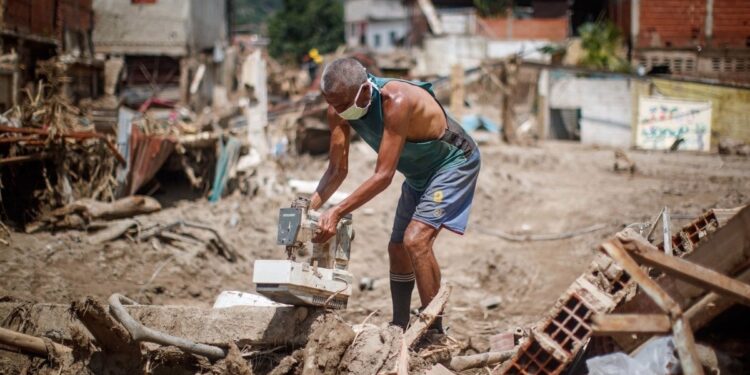 ACOMPAÑA CRÓNICA: VENEZUELA LLUVIAS. AME4750. LAS TEJERÍAS (VENEZUELA), 14/10/2022.- Personas buscan objetos para rescatar entre los escombros tras derrumbes provocados por las fuertes lluvias, hoy, en Las Tejerías (Venezuela). El bullicio de las personas y maquinarias limpiando las calles arrasadas por el deslave en Las Tejerías, en la zona central de Venezuela, poco se escuchaba en el cementerio, en la parte alta de esta localidad, donde este viernes Armando Monsalve terminaba la tumba de su hija, una de las, al menos, 50 personas fallecidas. EFE/ Miguel Gutiérrez