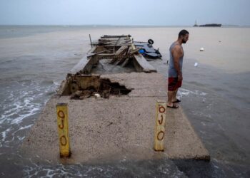 A man stands over a pier affected by the passing of Hurricane Fiona in Penuelas, Puerto Rico September 19, 2022.  REUTERS/Ricardo Arduengo