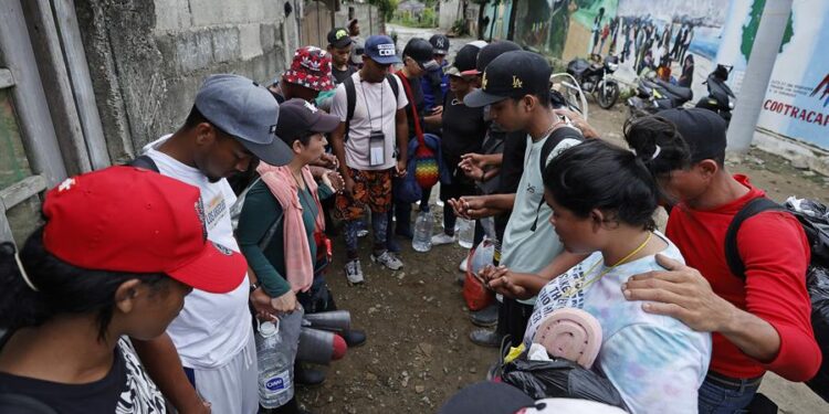 Fotografía del 12 de octubre de 2022 que muestra a migrantes venezolanos que rezan antes de iniciar un recorrido con la intención de llegar a Panamá para emprender una travesía con destino final en Estados Unidos, el 8 de octubre de 2022, a través del Tapón del Darién (Colombia). Moisés tardó 21 días en llegar desde Venezuela a México, en ruta hacia Estados Unidos, igual que otros migrantes que se enfrentan a un duro trayecto que recorren a ratos a pie, a caballo, en piragua, en bus y hasta en una carreta, en busca del sueño americano, del que muchos despertaron de golpe tras el anuncio de la nueva política migratoria del Gobierno norteamericano, que limita sus posibilidades de éxito. EFE/ Mauricio Dueñas Castañeda