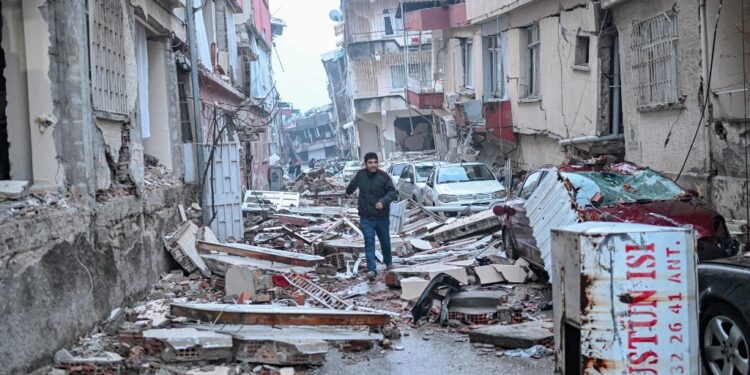A man runs along a street strewn with debris, in Hatay,  the day after a 7.8-magnitude earthquake struck the country's southeast on February 7, 2023. - Rescuers in Turkey and Syria braved frigid weather, aftershocks and collapsing buildings, as they dug for survivors buried by an earthquake that killed more than 5,000 people. Up to 23 million people could be affected by the massive earthquake that has killed thousands in Turkey and Syria, the WHO warned on Tuesday, promising long-term assistance. (Photo by BULENT KILIC / AFP)