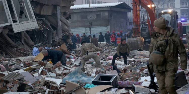 Un grupo de personas sobe escombros tratando de identificar víctimas debajo de ellos en Diyarbakir, Turquia.