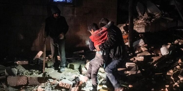 Un hombre se lleva a un niño herido luego de un terremoto en la ciudad de Jandaris, en el campo de la ciudad de Afrin, en el noroeste de Siria, en la parte rebelde de la provincia de Alepo..