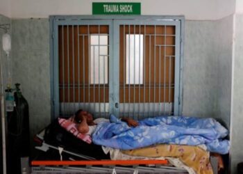 Un paciente yace en una cama frente a una puerta en un pasillo del Hospital Universitario de Mérida. Foto Marco Bello Reuters