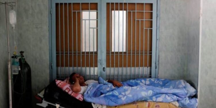 Un paciente yace en una cama frente a una puerta en un pasillo del Hospital Universitario de Mérida. Foto Marco Bello Reuters