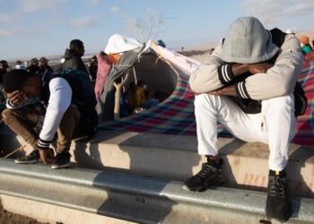 Migrantes permanecen a un lado de la vía mientras esperan soluciones a su situación migratoria, el 3 de mayo de 2023, en el paso fronterizo Chacalluta, en Arica (Chile). Jimir, Yuri y Belquis jamás se vieron aunque estuvieron en sitios parecidos, jamás hablaron, pero si lo hubieran hecho en la penúltima parada que les deparó su azarosa vida de migrantes, huyendo de Chile, se habrían sorprendido de qué parejos eran sus sueños rotos, sus miedos, su destino compartido. EFE/ Lucas Aguayo Araos