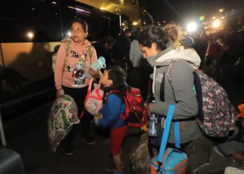 Venezuelan migrants board a bus that will take them to a shelter in the city of Arica, Chile on May 5, 2023. - A first repatriation flight for hundreds of Venezuelan migrants stranded on the border with Peru following the tightening of migration controls, will arrive in Chile early Sunday morning, Chilean Foreign Minister Alberto van Klaveren stated. The flight, sent by the Venezuelan government, will land in the city of Arica, to pick up migrants waiting on the Chilean side at the Chacalluta border crossing and another group in the Peruvian city of Tacna. (Photo by AGUSTIN MERCADO / AFP)