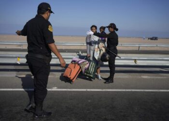 Un migrante venezolano y un niño son detenidos por la policía en Tacna, Perú, el viernes 28 de abril de 2023. (AP Foto/Martín Mejía)