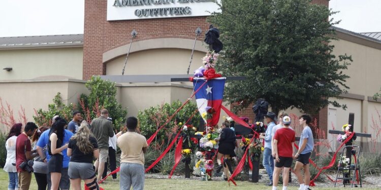 ALLEN, TEXAS - MAY 7: People watch as the construction of a wooden cross memorial is completed at the site of a fatal mass shooting a day earlier at Allen Premium Outlets on May 7, 2023 in Allen, Texas. According to reports, a shooter opened fire at the outlet mall, killing eight people. The gunman was then killed by an Allen Police officer responding to an unrelated call.   Stewart F. House/Getty Images/AFP (Photo by Stewart F. House / GETTY IMAGES NORTH AMERICA / Getty Images via AFP)