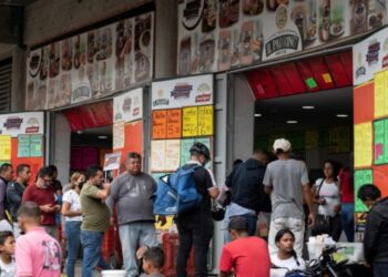 A group of people line up to buy sausages and cheese at a store near the Quinta Crespo municipal market that displays prices in dollars in Caracas on August 25, 2022. (Photo by Yuri CORTEZ / AFP)