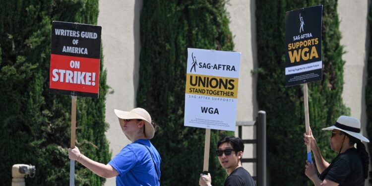 Hollywood writers and their supporters from the SAG AFTRA actors' union walk the picket line outside Warner Bros Studios in Burbank, California, June 30, 2023. Hollywood's summer of discontent could dramatically escalate this weekend, with actors ready to join writers in a massive "double strike" that would bring nearly all US film and television productions to a halt. The Screen Actors Guild (SAG-AFTRA) is locked in last-minute negotiations with the likes of Netflix and Disney, with the deadline fast approaching at midnight Friday (0700 GMT Saturday). (Photo by Robyn Beck / AFP)