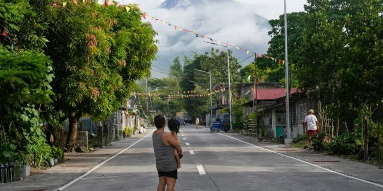 Una mujer y una niña miran hacia el volcán Mayon en Legazpi, provincia de Albay, noreste de Filipinas, el martes 13 de junio de 2023. (Foto AP/Aaron Favila)