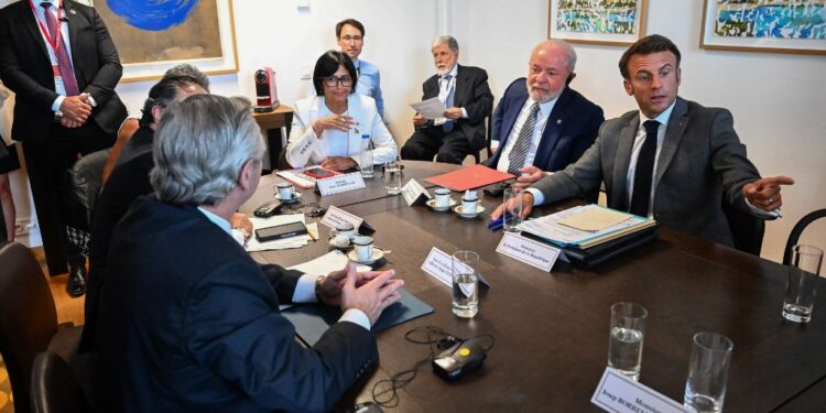 France's President Emmanuel Macron (R) gestures as he speaks with Vice President of Venezuela Delcy Rodriguez (2L), Brazil's President Luiz Inacio Lula da Silva (C), Colombia's President Gustavo Petro (from the back L) and Argentina's President Alberto Fernandez (from the back R) during a meeting on the sidelines of a summit of European Union-Community of Latin American and Caribbean States Summit (EU-CELAC) at The European Council Building in Brussels on July 17, 2023. (Photo by Emmanuel DUNAND / POOL / AFP)