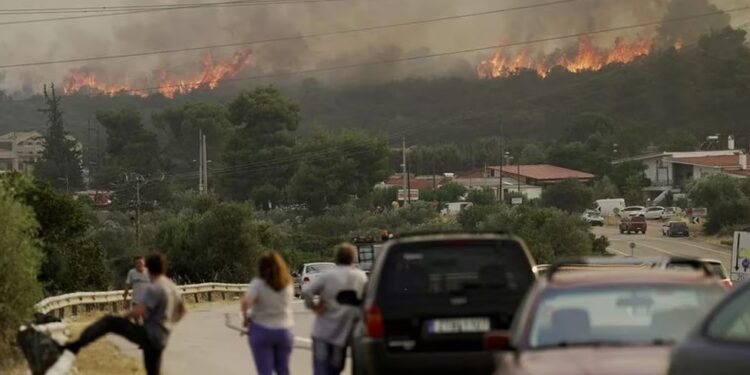 Varias personas miran cómo arde un incendio forestal cerca del pueblo de Agios Sotira (Reuters)
