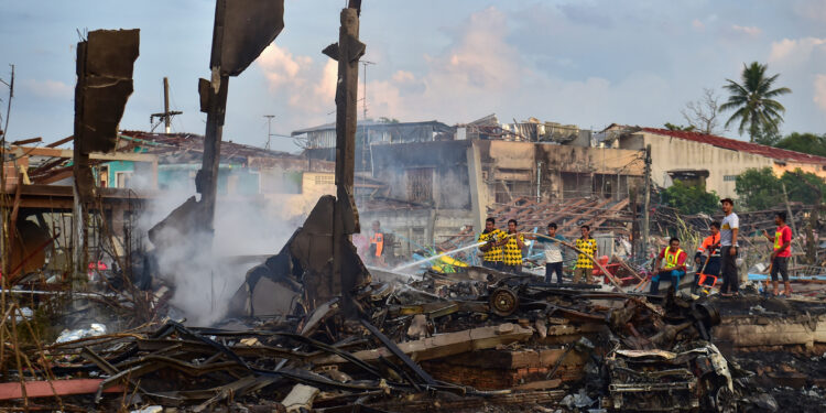 Thai firefighters put out embers around destroyed homes after an explosion ripped through a firework warehouse, killing nine people and injuring more than 100, in Sungai Kolok district in the southern Thai province of Narathiwat on July 29, 2023. (Photo by Madaree TOHLALA / AFP)