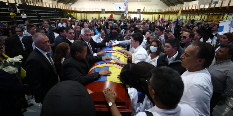 AME9921. QUITO (ECUADOR), 11/08/2023.- Varias personas rodean el féretro del candidato Fernando Villavicencio en un recinto ferial al que fue llevado para un velatorio público, hoy, en Quito (Ecuador). El féretro de Fernando Villavicencio, el candidato a la Presidencia de Ecuador asesinado el miércoles, salió del cementerio al que había sido trasladado para tener un breve velatorio público antes de regresar al camposanto y proceder con su inhumación. Después de haber sido velado de manera íntima y privada por familiares y allegados en un tanatorio de Quito, el féretro con los restos mortales de Villavicencio partió primero al cementerio y, luego de realizar allí una breve ceremonia, salió hacia un recinto ferial donde su círculo cercano había previsto un homenaje póstumo. EFE/ José Jácome