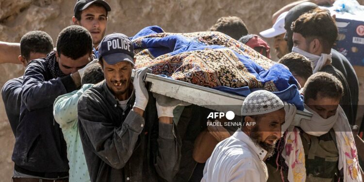 People carry the remains of a victim of the deadly 6.8-magnitude September 8 earthquake, in the village of Imi N'Tala near Amizmiz in central Morocco on September 10, 2023. - Using heavy equipment and even their bare hands, rescuers in Morocco on September 10 stepped up efforts to find survivors of a devastating earthquake that killed more than 2,100 people and flattened villages. (Photo by FADEL SENNA / AFP)