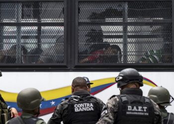 Members of the Bolivarian National Guard (GNB) stand guard as inmates aboard a bus are transferred outside the Tocoron prison in Tocoron, Aragua State, Venezuela, on September 20, 2023. Venezuela said Wednesday it had seized control of a prison from the hands of a powerful gang with international reach, in a major operation involving 11,000 members of its security forces. (Photo by Yuri CORTEZ / AFP)