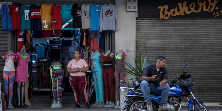 AME8626. CARACAS (VENEZUELA), 11/09/2023.- Personas trabajan junto a un local comercial, el 30 de agosto de 2023 en Caracas (Venezuela). La economía de Venezuela, que cayó un 7 % de enero a junio -según cálculos independientes-, vuelve a mostrar leves signos de mejora en algunos sectores, como el petrolero, lo que impulsará un crecimiento del 4 % en el segundo semestre respecto al mismo lapso de 2022, prevén expertos, aunque advierten que este incremento no compensará la caída de la primera mitad del año. EFE/ Miguel Gutiérrez