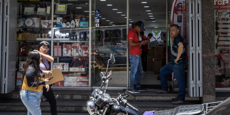 AME8626. CARACAS (VENEZUELA), 11/09/2023.- Personas acuden a un local comercial, el 30 de agosto de 2023 en Caracas (Venezuela). La economía de Venezuela, que cayó un 7 % de enero a junio -según cálculos independientes-, vuelve a mostrar leves signos de mejora en algunos sectores, como el petrolero, lo que impulsará un crecimiento del 4 % en el segundo semestre respecto al mismo lapso de 2022, prevén expertos, aunque advierten que este incremento no compensará la caída de la primera mitad del año. EFE/ Miguel Gutiérrez