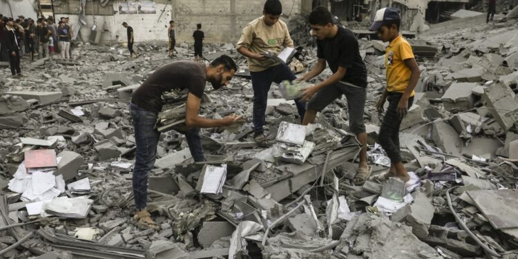 People salvage belongings from the rubble of a building levelled in an Israeli strike on Rafah in the southern Gaza Strip on October 15, 2023. Israel embarked on a withering air campaign against Hamas militants in Gaza after they carried out a brutal attack on Israel on October 7 that left more than 1,400 people killed in Israel. (Photo by Mohammed ABED / AFP)