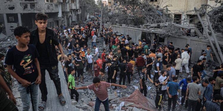 People gather in a neighbourhood in Rafah in the southern Gaza Strip, after it was hit by an Israeli strike on October 15, 2023. Israel embarked on a withering air campaign against Hamas militants in Gaza after they carried out a brutal attack on Israel on October 7 that left more than 1,400 people killed in Israel. (Photo by SAID KHATIB / AFP)